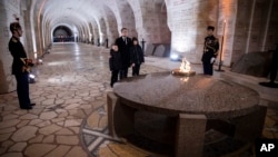 French President Emmanuel Macron pays his respects with children at the Ossuary of Douaumont near Verdun, northeastern France, Nov. 6, 2018 during ceremonies marking the centenary of the end of World War I.