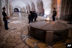 FILE - French President Emmanuel Macron pays his respects with children at the Ossuary of Douaumont near Verdun, northeastern France, Nov. 6, 2018, during ceremonies marking the centenary of the end of World War I.