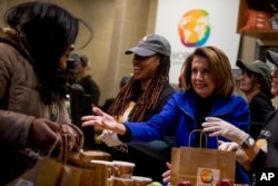 House Speaker Nancy Pelosi of California, center, helps give out food at World Central Kitchen, the not-for-profit organization started by Chef Jose Andres, Jan. 22, 2019, in Washington.