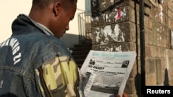 FILE - A man reads a newspaper as he walks along a street in Addis Ababa.