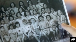 Joan Rodby points to herself in a 1942 photo, in Makawao, Hawaii on Friday, Nov. 18, 2016. After the Pearl Harbor attack, schools required students, including Rodby's childhood friends Emma Veary and Florence Seto, to carry gas masks with them at all times - even when posing for their class photo. 