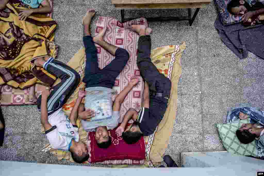 Palestinian men rest as dozens of displaced families from the northern Beit Hanun district of the Gaza Strip take refuge at a UN girl&#39;s preparatory school in Jabalia.