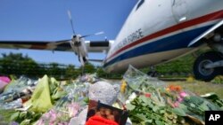 Flowers and a teddy bear are placed in front of a plane prior a ceremony to mark the return of the first bodies of passengers and crew killed in the downing of Malaysia Airlines Flight 17, Eindhoven military air base, July 23, 2014.