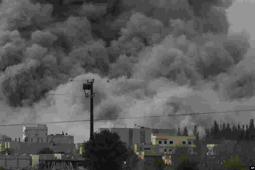 Une épaisse fumée, des débris et des flammes s&rsquo;élèvent après une frappe aérienne de la coalition menée par les Etats-Unis à Kobani, en Syrie alors que des combats s&rsquo;intensifient entre les Kurdes Syriens et des combattants de l&rsquo;Etat Islamique, comme observé depuis le faubourg de Suruc, à la frontière Turco-Syrienne, dimanche le 12 octobre 2014. (AP Photo/Lefteris Pitarakis) 
