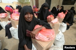 FILE - Women sit next to food aid delivered by the International Committee of the Red Cross to internally displaced people in the Red Sea port city of Hodeida, Yemen, July 21, 2018.