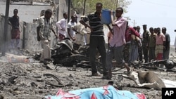 Residents gather near the covered remains of a suicide bomber at the scene of an attack along a street in Somalia's capital Mogadishu. A truck bomb killed at least 65 people at government buildings in the heart of Somalia's capital on Tuesday, an ambulanc