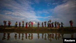 Bayangan sosok pengungsi Rohingya yang melarikan diri dari Myanmar ke Palang Khali, dekat Cox's Bazar, Bangladesh, terpantul di genangan air hujan, sepanjang tanggul di tepi sawah, 2 November 2017. (Foto: dok).