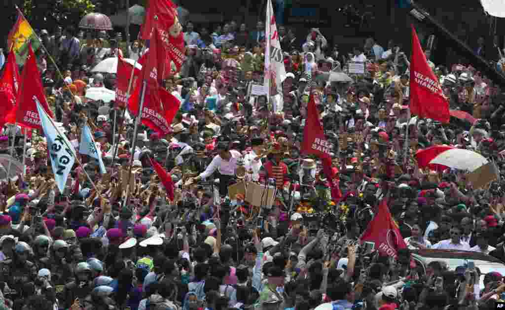 Presiden&nbsp;Joko Widodo menyalami warga di tengah kerumunan rakyat dalam parade jalanan menyusul pelantikannya di Jakarta (20/10). (AP/Mark Baker) 