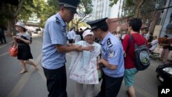 Petugas polisi China mencoba menyingkirkan wanita yang melancarkan protes dengan spanduk bertuliskan "tidak adil" di luar gedung pengadilan di kota Jinan, propinsi Shandong, Cina timur (21/8).