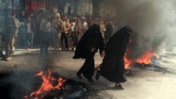 Women run past burning tires during protests against the deteriorating economic situation and the devaluation of the local currency, in Taiz, Yemen, Sept. 27, 2021.