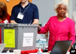 Broward County Supervisor of Elections Brenda Snipes, right, shows a ballot box that was found in a rental car after the elections and turned out to only contain election day supplies, as election employees sort ballots and prepare to count them, Monday, Nov. 12, 2018, in Lauderhill, Florida.
