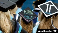 FILE - Graduates, including one looking for a job, are seated during George Washington University's commencement exercises on the National Mall, Sunday, May 17, 2015 in Washington, DC.