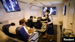 A staff dressed as a flight attendant serves meals to customers at First Airlines, that provides VR flight experiences, including 360-degree tours of cities and meals, amid the COVID-19 pandemic in Tokyo, Japan August 12, 2020. (REUTERS/Kim Kyung-Hoon)