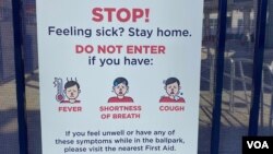 A sign outside of Nationals Park in Washington, D.C. tells baseball fans to stay away from the stadium if they do not feel well. (VOA/Dan Friedell)