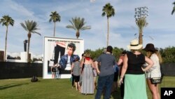 Espectadores do festival "Desert Trip" em Los Angeles posam junto a um cartaz do álbum de Bob Dylan "Highway 61 Revisited"