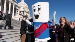 FILE - A man dressed as "Build Back Better Bill" wears a sash saying, "On to the Senate," Nov. 19, 2021, on Capitol Hill.