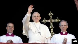 Pope Francis, flanked by Master of Ceremonies Bishop Guido Marini, waves to faithful during the Urbi et Orbi Christmas' day blessing from the main balcony of St. Peter's Basilica at the Vatican, Dec. 25, 2017. 