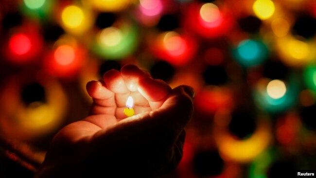 FILE - A woman holds a candle during a commemoration ceremony in Kiev on November 22, 2014. (REUTERS/Gleb Garanich)