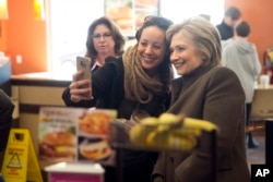 Democratic presidential candidate Hillary Clinton makes a selfie with a customer Sunday, Feb. 7, 2016, at a Dunkin' Donuts in Manchester, N.H.