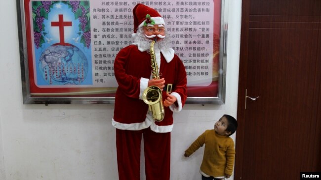 2018年12月22日,中国云南省鹿泉彝族苗族自治县的基督教堂,一个男孩看着圣诞老人像。