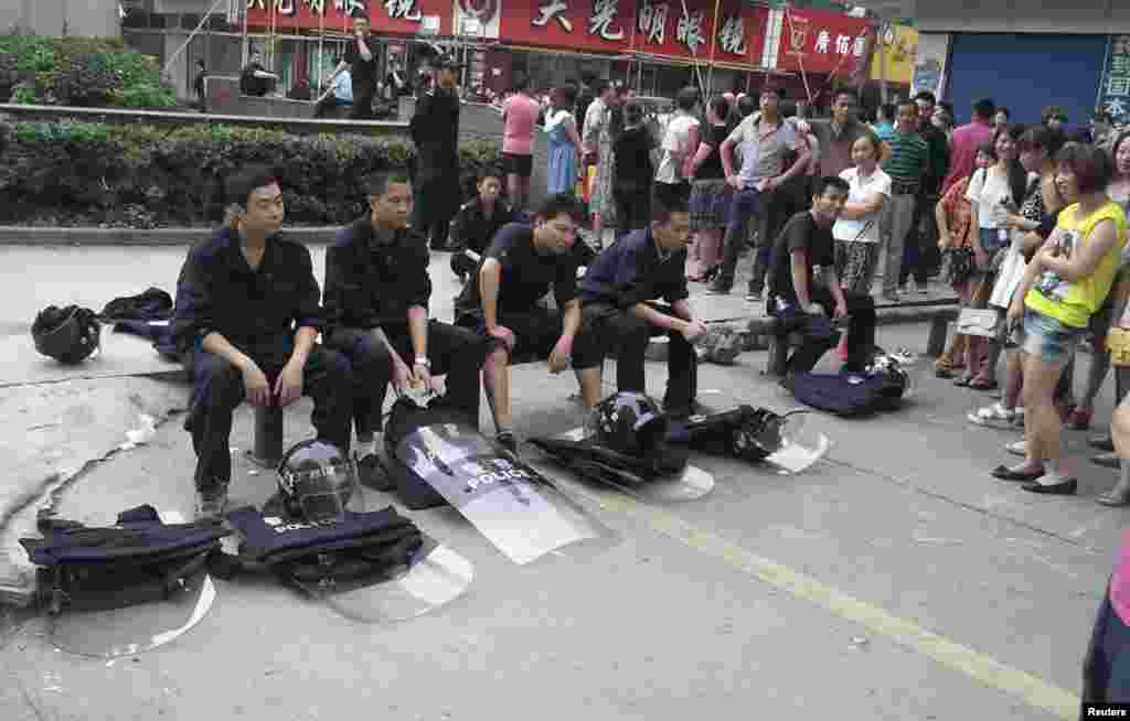 Riot police (L) sit next to local residents as they take a rest during a protest in Shifang, Sichuan province, China, July 3, 2012. 