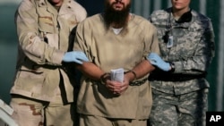 FILE - A shackled detainee leaves an administrative review board hearing at the Guantanamo Bay U.S. Naval Base in Cuba, Dec. 6, 2006. The Justice Department has blocked efforts to allow guilty pleas entered via videoconference. 