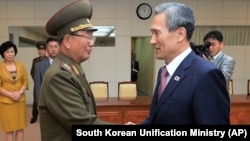 South Korean presidential security adviser Kim Kwan-jin, right, shakes hands with Hwang Pyong So, North Korea's top political officer for the Korean People's Army, after meeting at the border village of Panmunjom in Paju, South Korea, Aug. 25, 2015. 