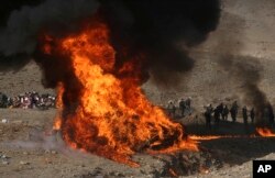 FILE - Afghan security personnel watch as flames and smoke rise after opium and narcotics are burned in a ceremony in Kabul, Afghanistan, Dec. 20, 2016.