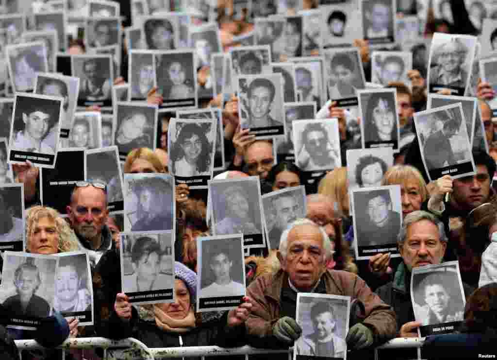 People hold up portraits of victims of the 1994 bombing of the Argentine Israeli Mutual Association (AMIA) community center as they gather to commemorate the 24th anniversary of the attack in Buenos Aires, Argentina, July 18, 2018.
