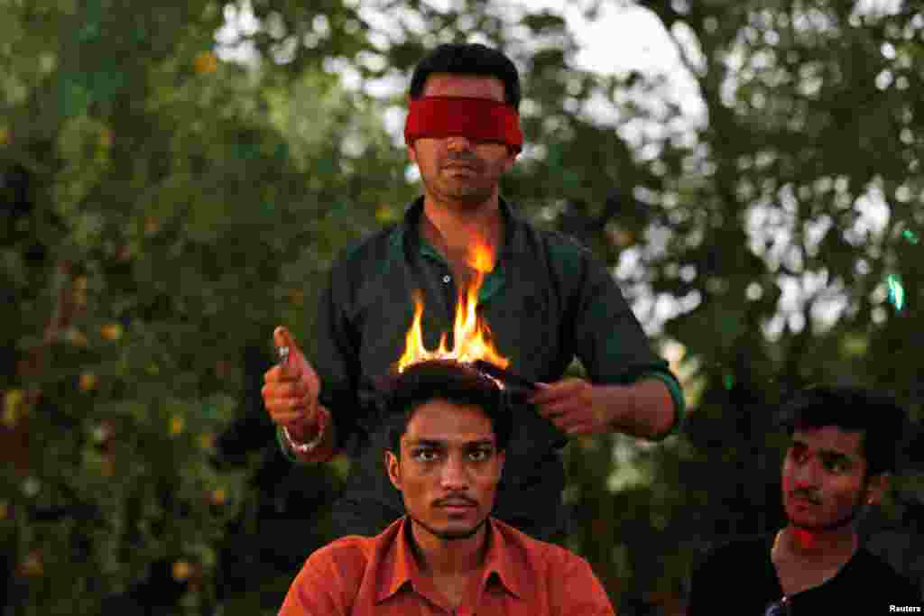 Hair artist Vishnu Limbachiya styles a man&#39;s hair while wearing a blindfold at a park in Ahmedabad, India.