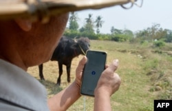 FILE - A man uses his mobile phones to check Facebook in Naypyidaw on March 16, 2021, as Myanmar authorities ordered telecommunication companies to restrict their services on the mobile data networks, following the February 1 military coup. (Photo by AFP)