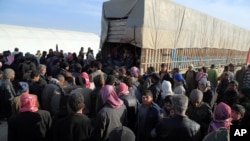 FILE - Syrians fleeing the conflicts in the A'zaz region congregate at the Bab al-Salam border gate, Syria, Feb. 5, 2016. 