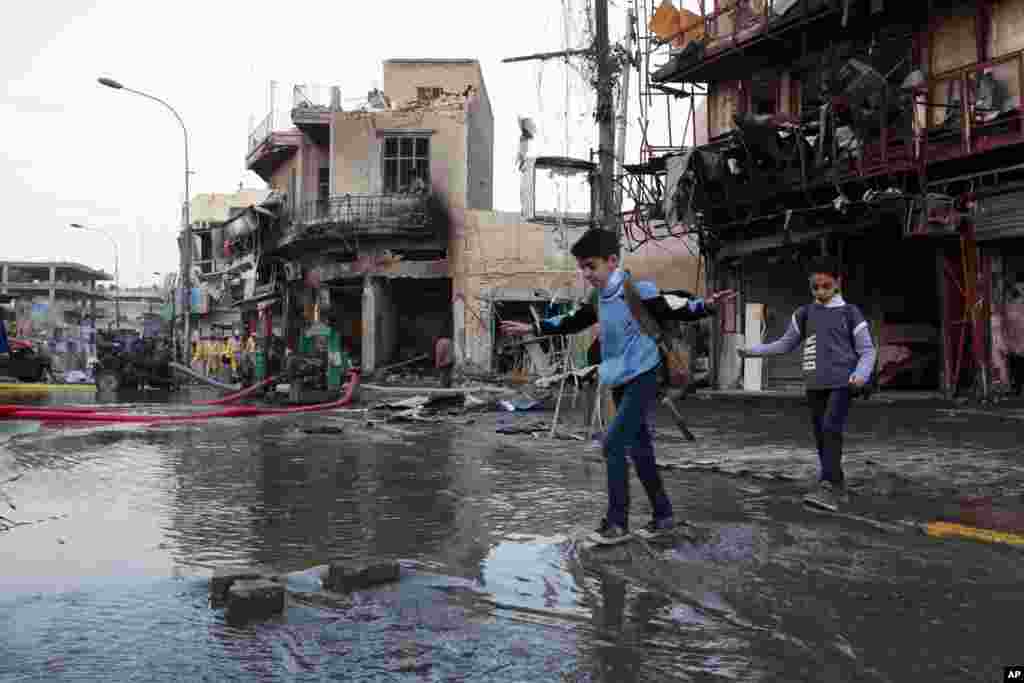 Anak-anak berjalan ke sekolah di lokasi serangan bom mobil, Baghdad, Irak, 18 Februari 2014.