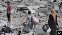 Người dân Palestine đem theo đồ đạc còn sót lại sau khi nhà của họ ở thị trấn Beit Hanoun, dải Gaza, gần biên giới với Israel, bị những trận bom tàn phá nặng nề.