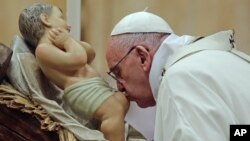 Paus Fransiskus mencium patung bayi Yesus pada malam Natal di basilika Santo Petrus, Vatikan Kamis malam (24/12).