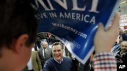 Republican presidential candidate and former Massachusetts Governor Mitt Romney is framed by a campaign sign held by a supporter as he greets the crowd after a campaign rally at Pinkerton Academy in Derry, New Hampshire, January 7, 2012.