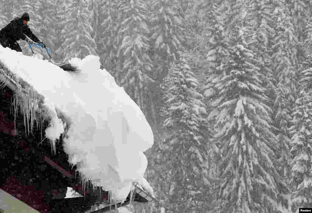 A man removes snow from a roof during a winter storm in Filzmoos, Austria.