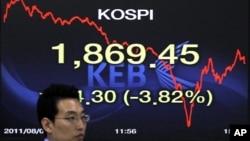 A foreign currency dealer of the Korea Exchange Bank walks past a screen displaying the Korea Composite Stock Price Index (KOSPI) at the bank's dealing room in Seoul August 8, 2011.