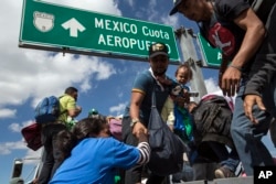 U.S.-bound Central American migrants get on to a truck for a a free ride, as part of a thousands-strong caravan moving through Puebla, Mexico, Nov. 5, 2018.