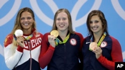 美国金牌得主金恩在女子100米蛙泳的颁奖仪式上，旁边是银牌得主俄罗斯队员艾菲莫娃和铜牌得主美国队员麦利。
