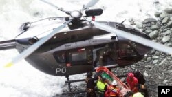 In this photo provided by the government news agency Andina, rescue workers surround an injured man on a stretcher who was lifted up from the site of a bus crash at the bottom of a cliff, after the bus was hit by a tractor-trailer rig in Pasamayo, Peru, J