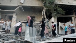 Warga Palestina memeriksa rumahnya yang terkena serangan udara Israel di kota Gaza (10/7).