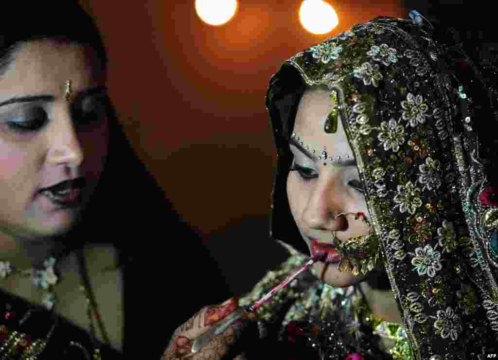 A Pakistani Hindu bride gets final make-up applications from a relative at a mass-wedding ceremony in Karachi. Some 50 Hindu couples participated in the ceremony organized by the Pakistan Hindu Council.