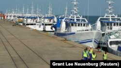 Patrulha de segurança passa por barcos da EMATUM na doca de Maputo.