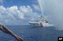 FILE - Chinese coast guard members approach Filipino fishermen as they confront each other off Scarborough Shoal in the South China Sea, also called the West Philippine Sea, Sept. 23, 2015.