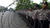 Indonesian police stand behind barb wire outside the presidential palace as demonstrators from an Indonesian university held a protest against the oil price increase across the street in Jakarta, Nov. 19, 2014. 