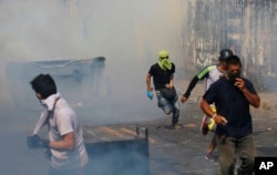 Người biểu tình tháo chạy tránh hơi cay của binh lính của lực lượng Vệ binh Quốc gia ở Urena, Venezuela, gần biên giới với Colombia, ngày 23 tháng 2, 2019.