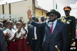 FILE - South Sudan President Salva Kiir waves as he greets schoolchildren at Juba International Airport, Sept. 13, 2018, after returning from Addis Ababa, where the latest peace agreement with opposition leader Riek Machar was finalized.