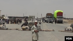 FILE - A boy stands at the closed Chaman border crossing between Pakistan and Afghanistan with trucks seen stranded in the background.