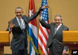 FILE - Cuban President Raul Castro, right, lifts up the arm of President Barack Obama at the conclusion of their joint news conference at the Palace of the Revolution, in Havana, Cuba, March 21, 2016.